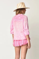 Woman wearing washed pink coquette shirt and skirt with a hat against a white background