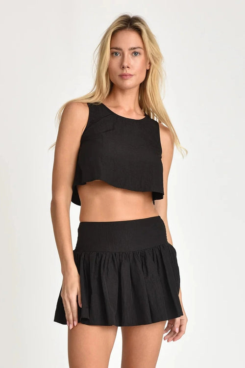 Woman wearing a black Nini top and skirt on a white background