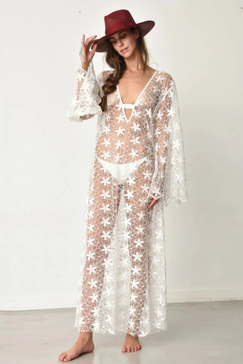 Woman wearing Tuyo white lace dress with bell sleeves and a red hat from muche et muchette